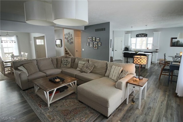 living area with stairs, dark wood-type flooring, and visible vents