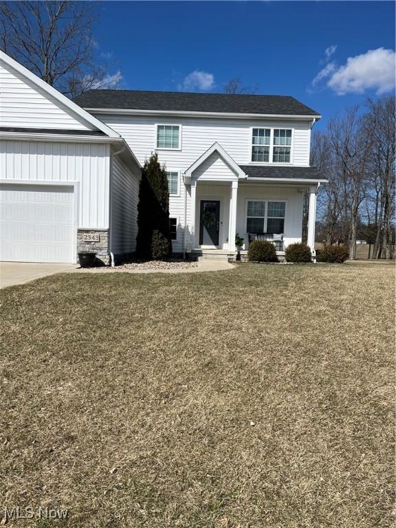 view of front of home with board and batten siding, a front lawn, a garage, and driveway