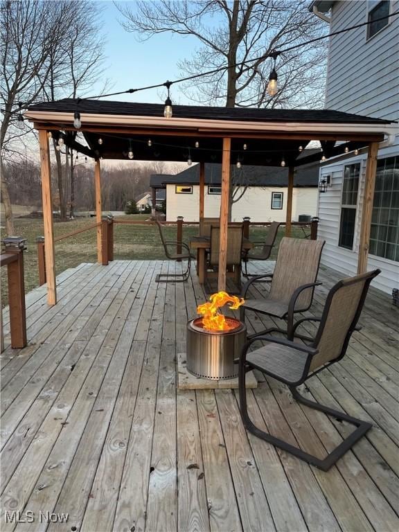 deck with outdoor dining space and an outdoor fire pit