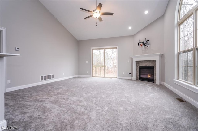 unfurnished living room with high vaulted ceiling, a tile fireplace, ceiling fan, and carpet