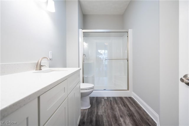 bathroom featuring a shower with door, wood-type flooring, vanity, and toilet