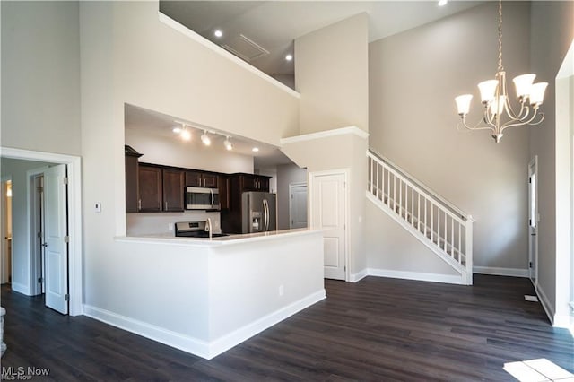 kitchen with dark brown cabinets, stainless steel appliances, a high ceiling, dark hardwood / wood-style flooring, and decorative light fixtures