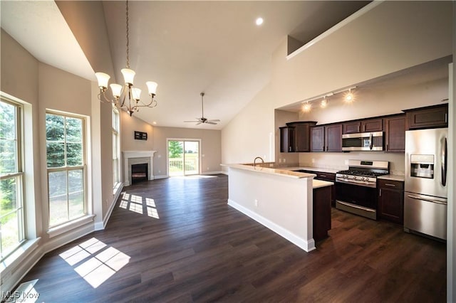 kitchen featuring dark brown cabinetry, decorative light fixtures, high vaulted ceiling, appliances with stainless steel finishes, and dark hardwood / wood-style floors