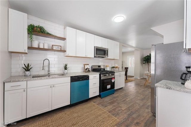 kitchen featuring appliances with stainless steel finishes, dark hardwood / wood-style floors, sink, white cabinets, and light stone counters