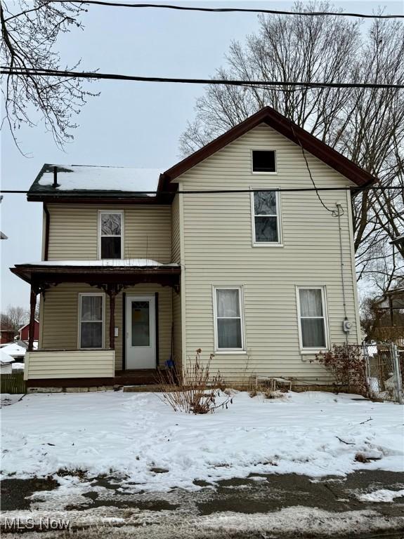 snow covered property with covered porch