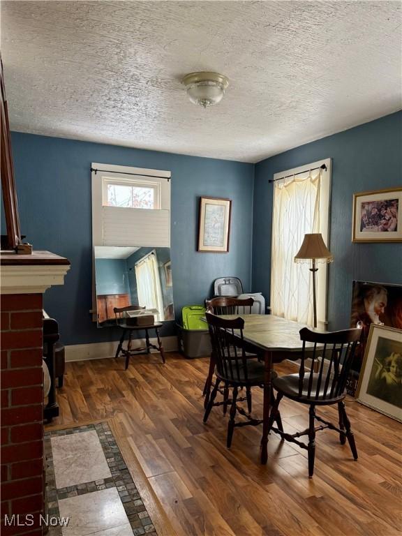 dining space featuring a brick fireplace, dark hardwood / wood-style floors, and a textured ceiling