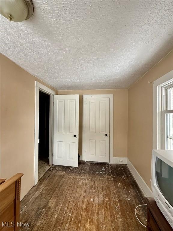 unfurnished bedroom featuring dark hardwood / wood-style flooring and a textured ceiling