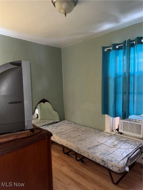 bedroom with cooling unit and light hardwood / wood-style flooring