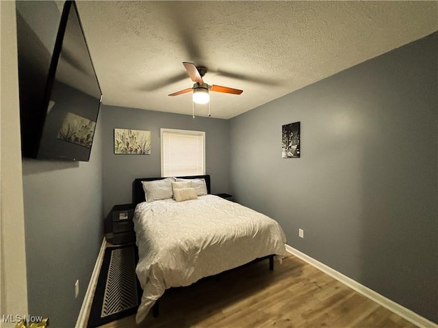 bedroom featuring hardwood / wood-style flooring, a textured ceiling, and ceiling fan