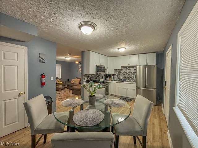 dining space with sink, light hardwood / wood-style flooring, and a textured ceiling