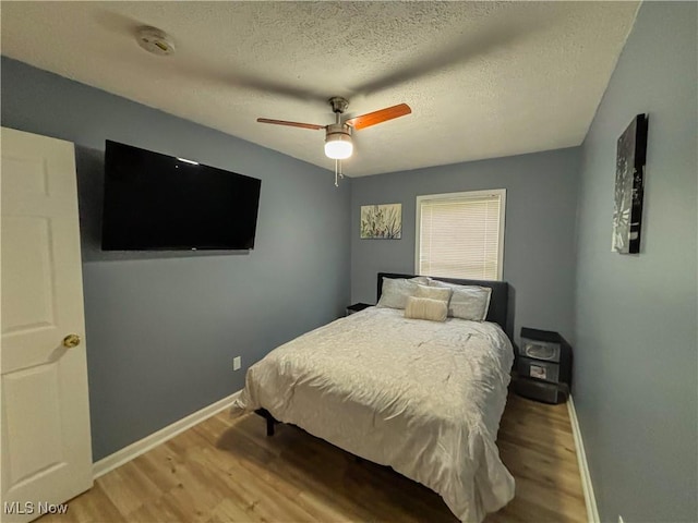 bedroom featuring hardwood / wood-style floors, a textured ceiling, and ceiling fan