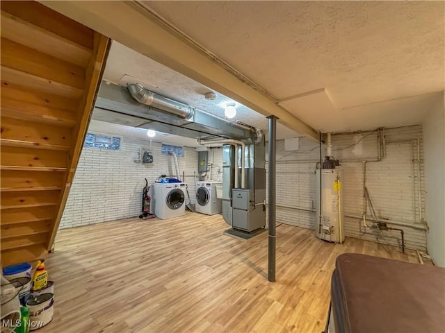 basement featuring hardwood / wood-style flooring, washer and clothes dryer, water heater, heating unit, and brick wall