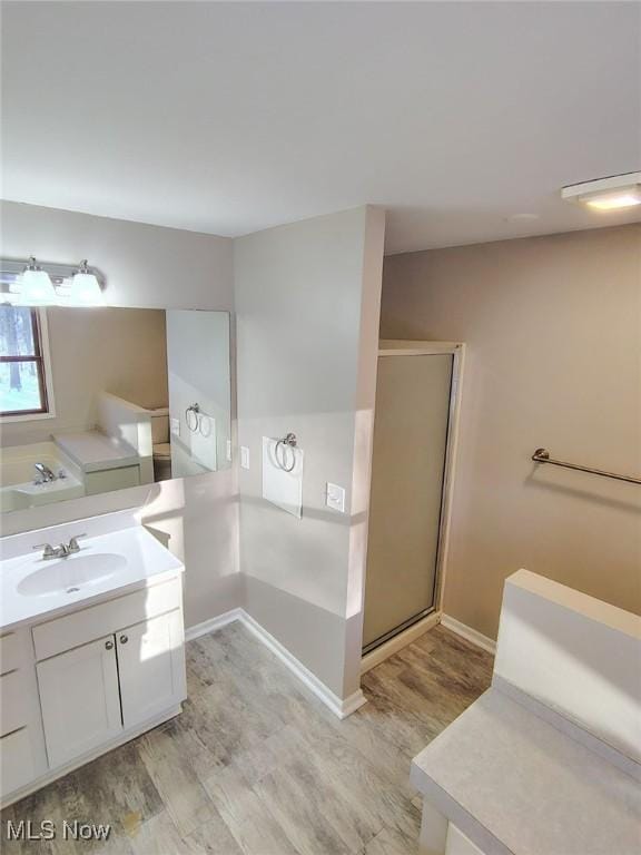 bathroom with independent shower and bath, vanity, and hardwood / wood-style flooring