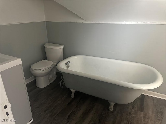 bathroom with hardwood / wood-style flooring, a tub to relax in, and toilet