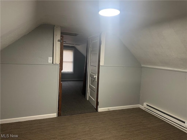 additional living space with a baseboard radiator, lofted ceiling, and dark carpet