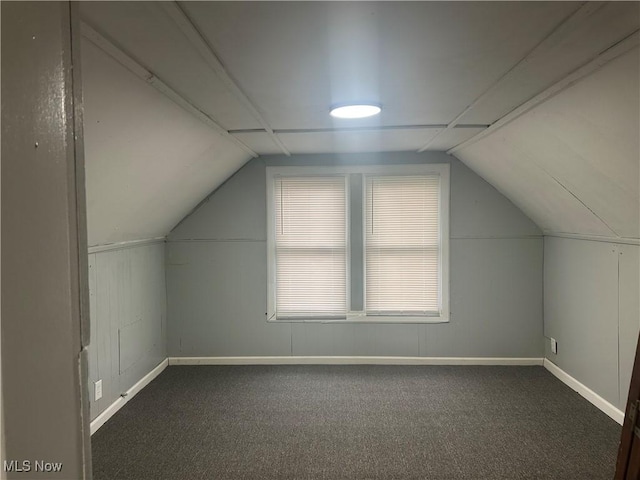 additional living space featuring vaulted ceiling and dark carpet