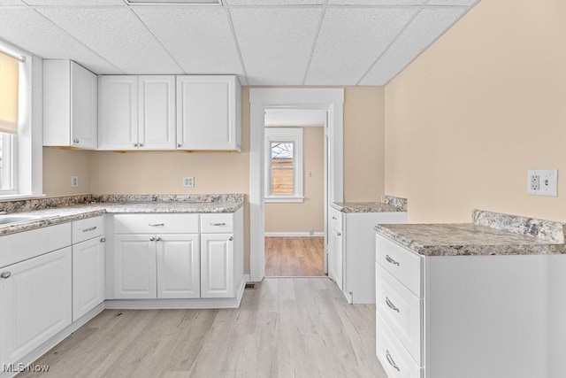 kitchen featuring a paneled ceiling, light hardwood / wood-style floors, and white cabinets