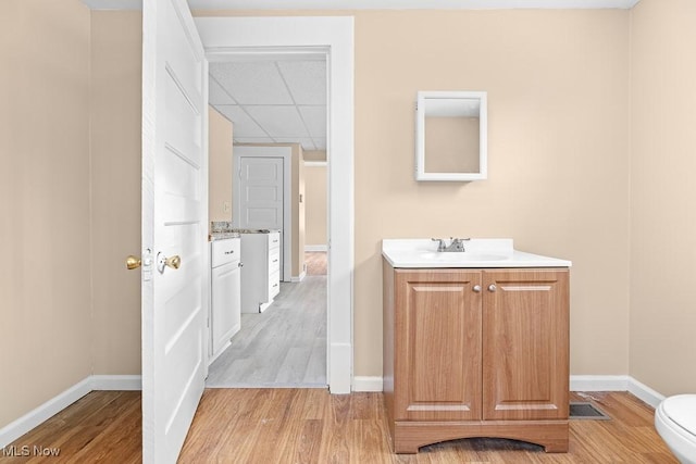 bathroom featuring sink, a paneled ceiling, hardwood / wood-style floors, and toilet