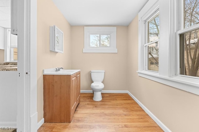 bathroom featuring a healthy amount of sunlight, vanity, wood-type flooring, and toilet