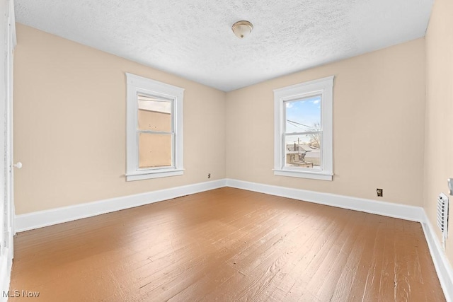 empty room with hardwood / wood-style floors and a textured ceiling