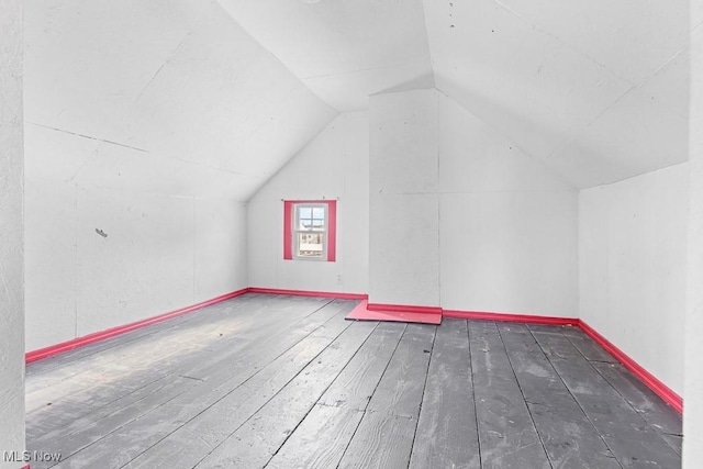 additional living space featuring dark wood-type flooring and lofted ceiling