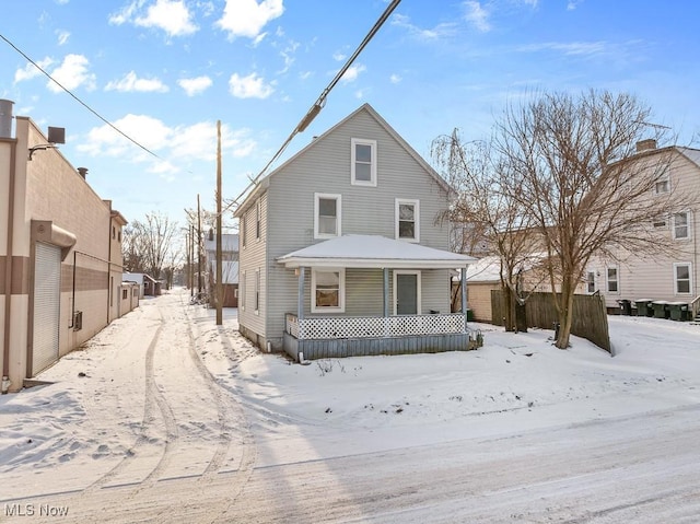 snow covered back of property featuring a porch