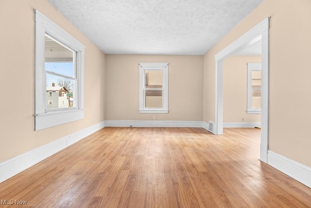 empty room featuring a textured ceiling and light hardwood / wood-style floors