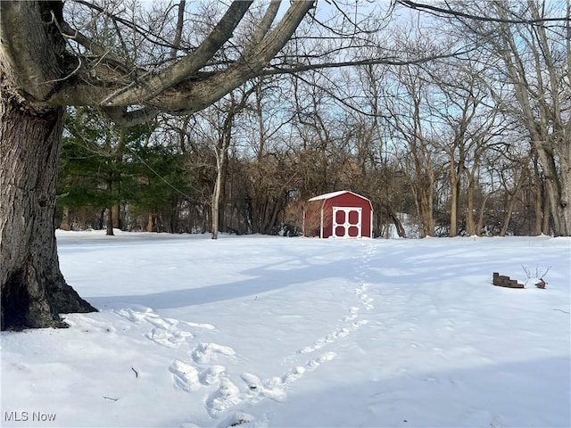 yard layered in snow featuring a storage shed