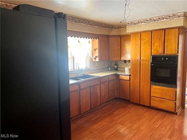 kitchen with light wood-type flooring, sink, and black appliances