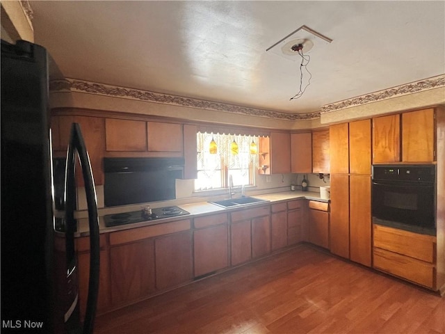 kitchen featuring sink, light hardwood / wood-style flooring, and black appliances