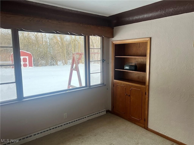 unfurnished room featuring a baseboard heating unit and light colored carpet