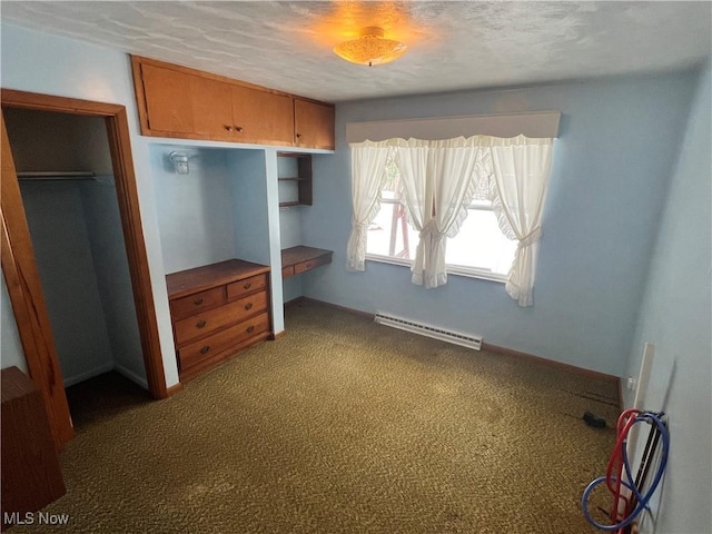 unfurnished bedroom with built in desk, a closet, baseboard heating, and carpet flooring