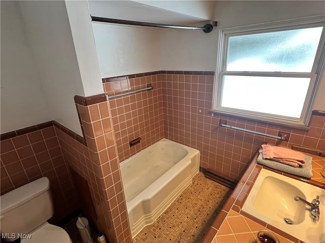 bathroom with a healthy amount of sunlight, tile walls, and toilet