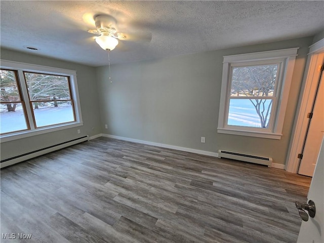 spare room featuring hardwood / wood-style flooring, a textured ceiling, and baseboard heating