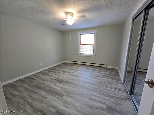 spare room with a baseboard radiator, wood-type flooring, and a textured ceiling