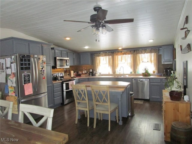 kitchen featuring a kitchen island, appliances with stainless steel finishes, lofted ceiling, sink, and dark hardwood / wood-style flooring