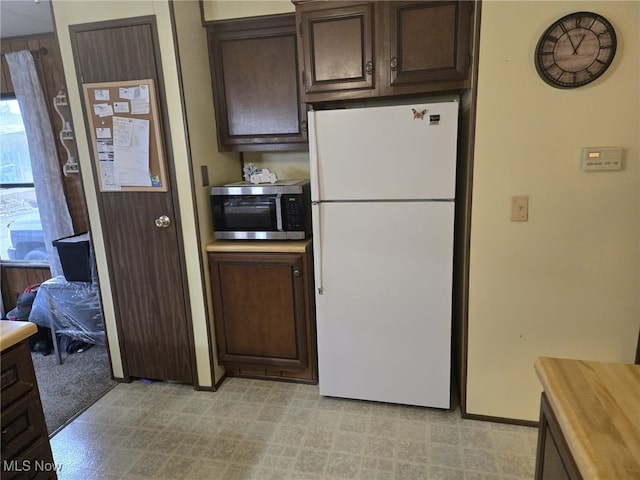 kitchen with white refrigerator and dark brown cabinetry