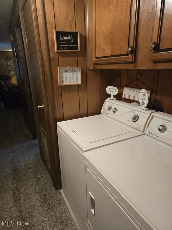 clothes washing area with cabinets, dark carpet, independent washer and dryer, and wood walls