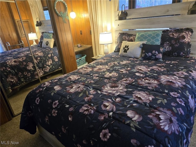 carpeted bedroom with a closet and wood walls