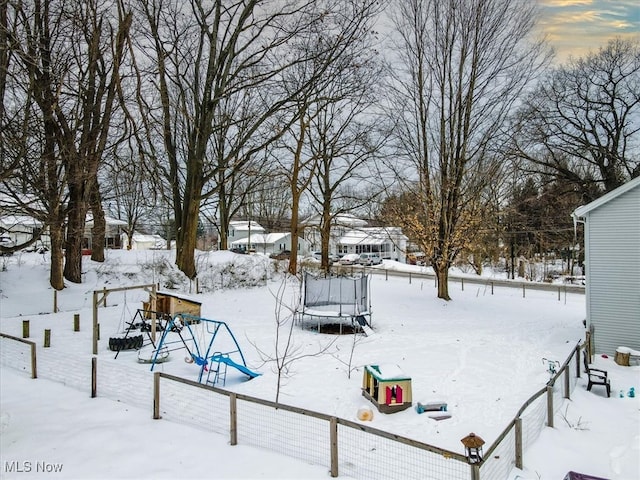 yard covered in snow featuring a playground and a trampoline