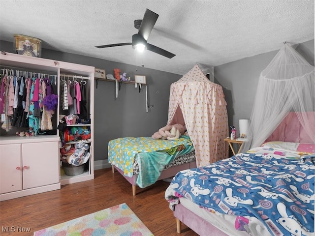 bedroom featuring dark hardwood / wood-style flooring, a textured ceiling, ceiling fan, and a closet