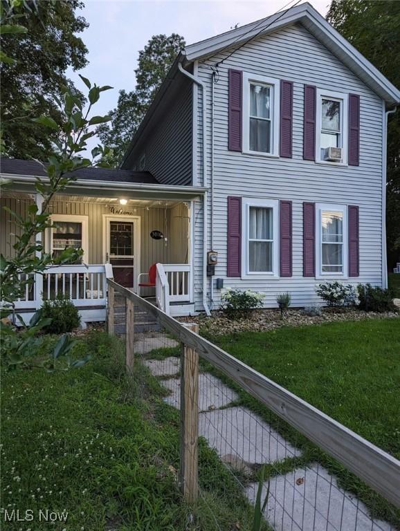 view of front of house featuring cooling unit, a front lawn, and covered porch