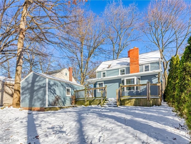 snow covered back of property with a deck