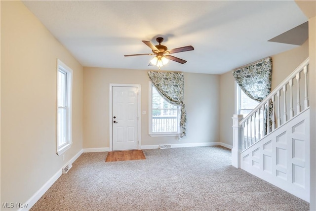 foyer entrance featuring ceiling fan and carpet