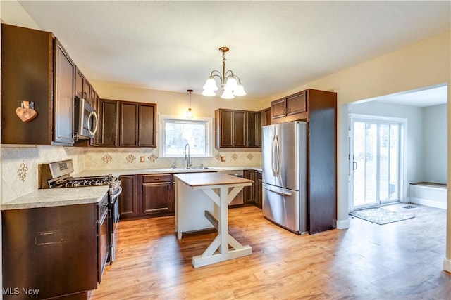 kitchen with hanging light fixtures, plenty of natural light, stainless steel appliances, a center island, and decorative backsplash