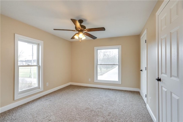 carpeted spare room featuring a wealth of natural light and ceiling fan