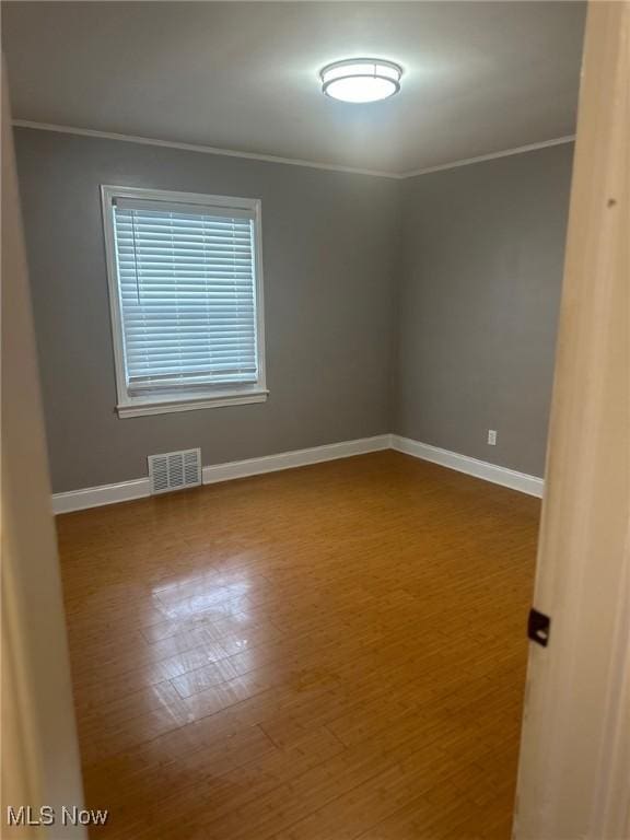 spare room featuring hardwood / wood-style flooring and ornamental molding