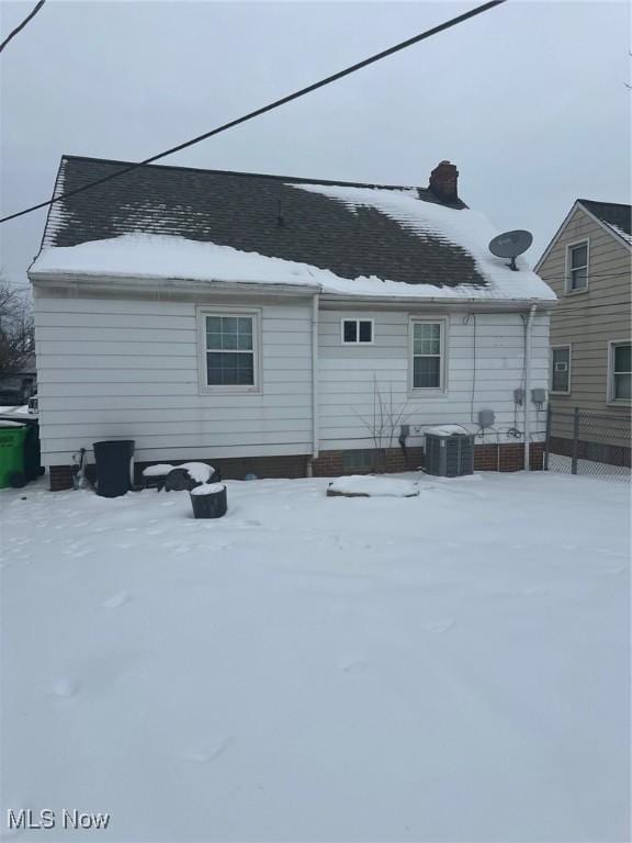 snow covered house featuring central AC unit