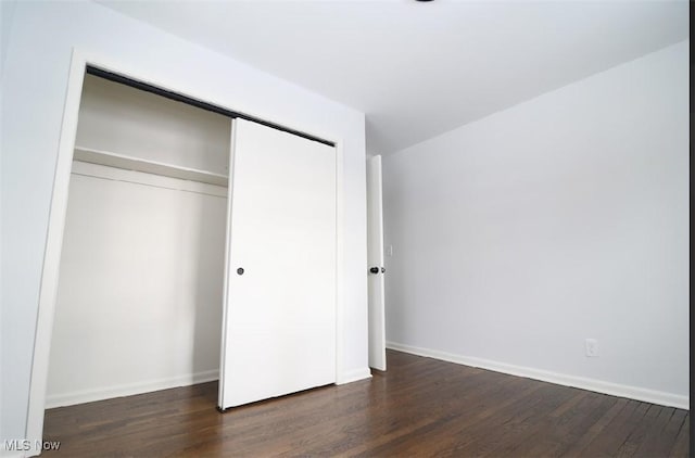 unfurnished bedroom featuring dark hardwood / wood-style flooring and a closet