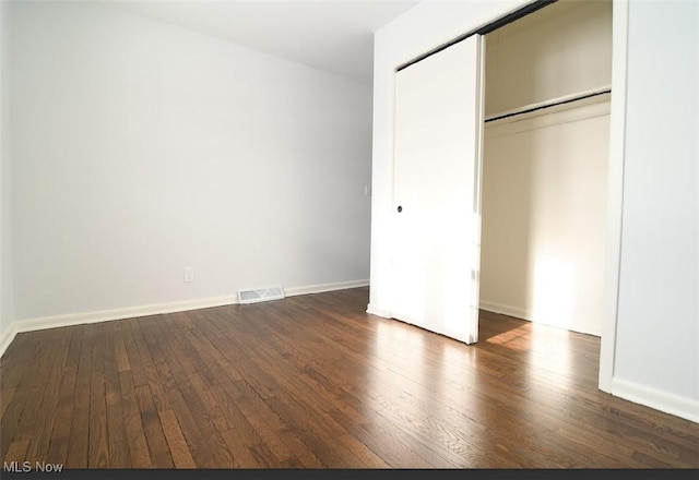 unfurnished bedroom with dark wood-type flooring and a closet